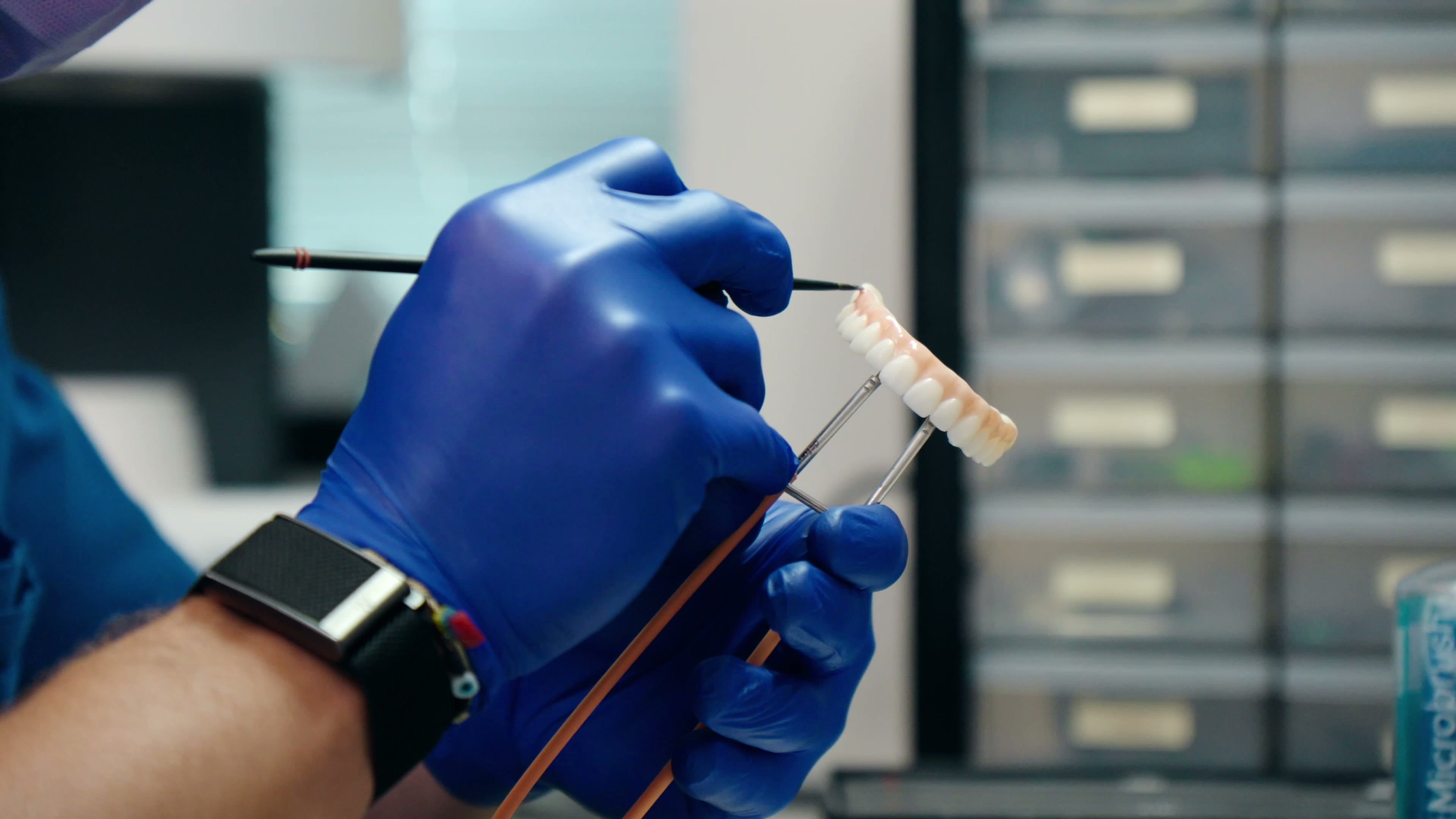 A gloved hand holding an instrument beside the treatment cabinet