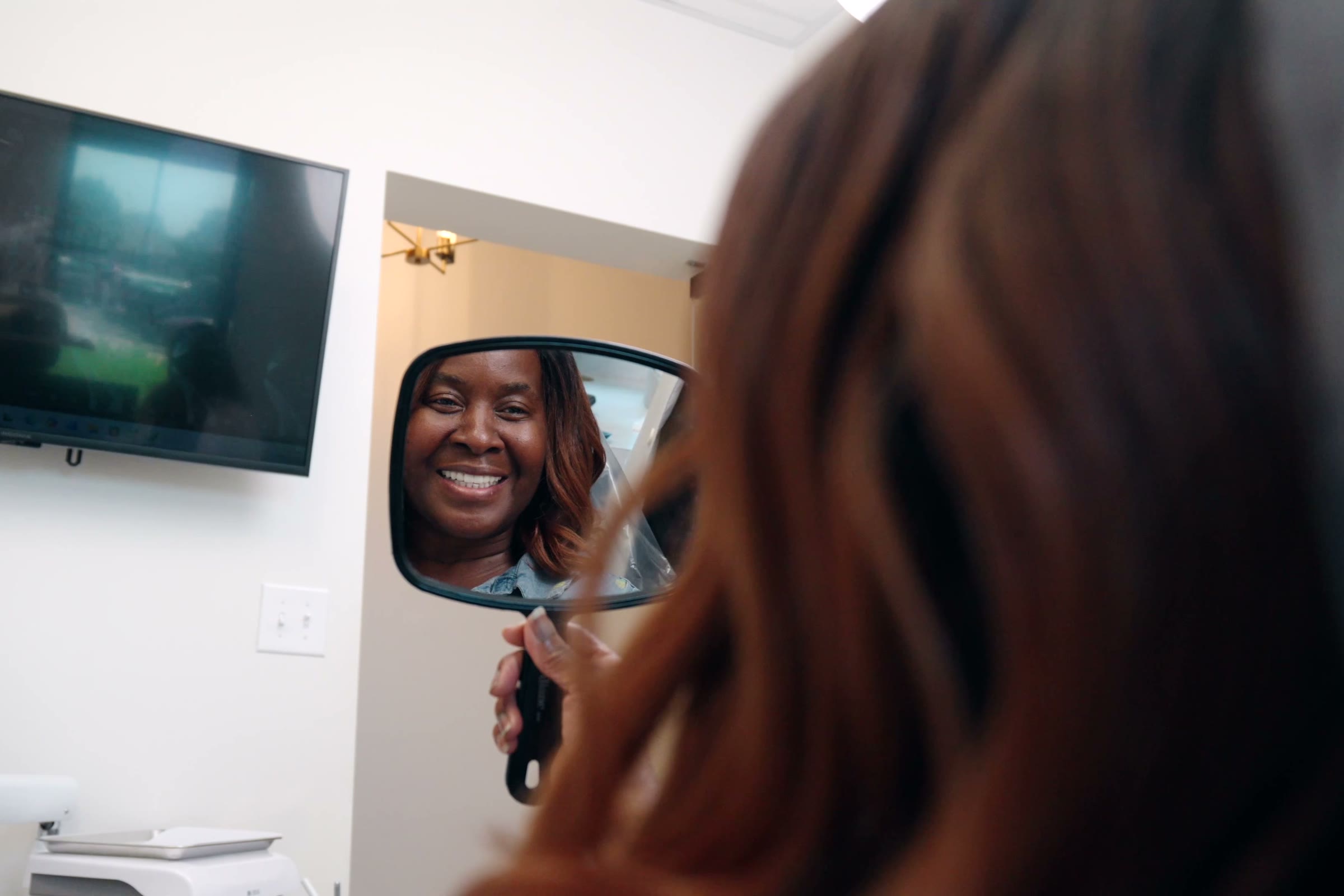 A patient looking at her new smile in a hand mirror