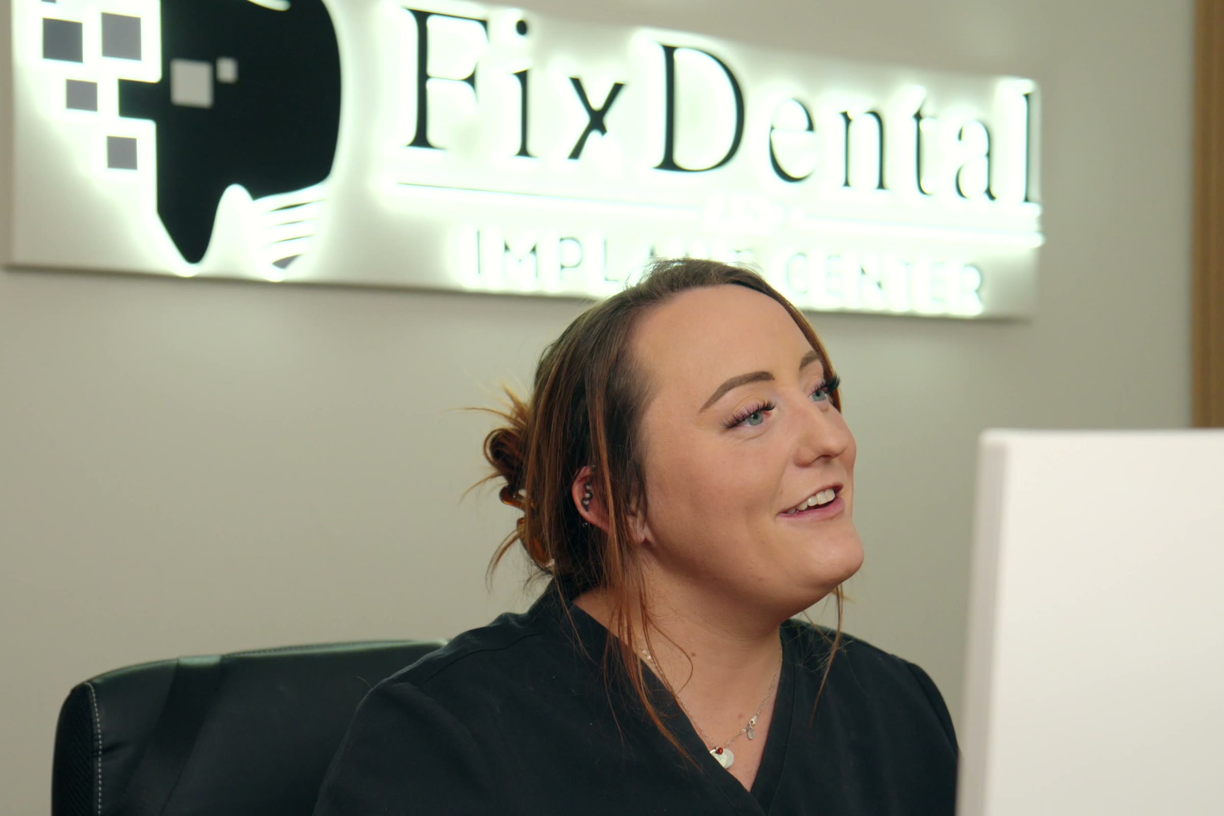 A FixDental team member at the practice, under the sign